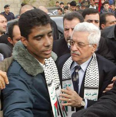 Zakaria Zubeidi accompanied by Palestinian Authority leader Mahmoud Abbas while Zakaria Zubeidi wearing a blue and gray jacket and a sash