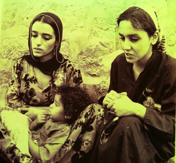 Zana Muhsen wearing black dress and Nadia carrying her daughter while sitting on the ground
