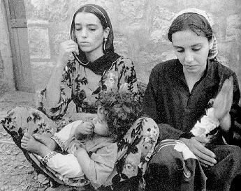 Zana Muhsen wearing black dress and Nadia carrying her daughter while sitting on the ground