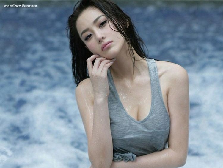 Zhang Xinyu posing seductively near a pool with her left hand on her chin and wearing a gray sleeveless shirt.