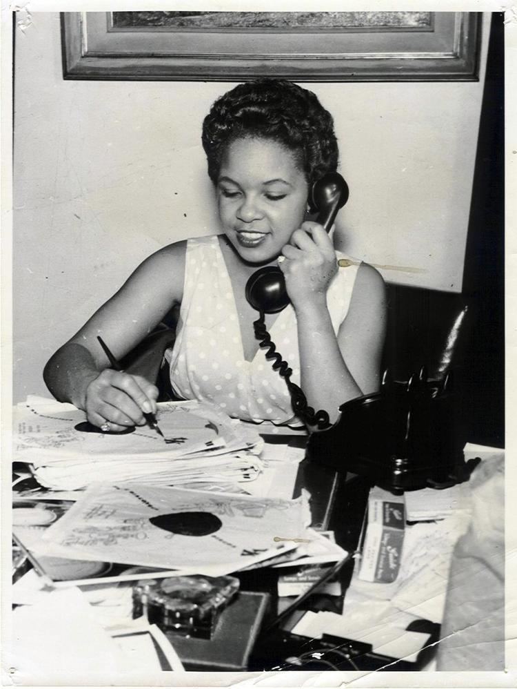 Zola Taylor smiling while holding a telephone and a pen.