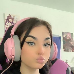 Zookdook with a duck face pose while wearing pink and gray headphone